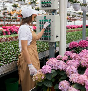 female gardener using modern equipment watering flowers